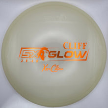 A translucent pale yellow disc golf disc with orange foil stamping reading 'CLIFF GLOW' and 'Xa Clima', resting on a white foam insert.
