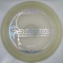 A translucent pale yellow Discraft Raptor Seasonal Med Ball disc golf disc resting on a white foam insert, with a purple surface visible at the right edge.