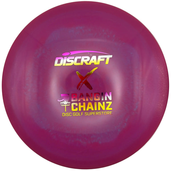 A magenta pink Discraft disc golf disc with 'BANGIN' CHAINZ' and 'DISC GOLF SUPERSTORE' printed on it, resting on a white surface.