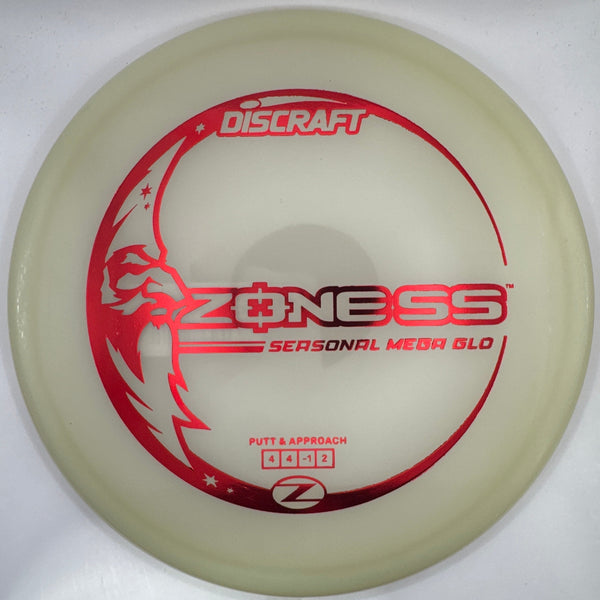 A Discraft Z-NESS Seasonal Aerfoam disc golf disc in translucent cream with red and white graphics, shown inside its white foam packaging insert.