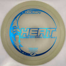 A Discraft Heat Personal Mesh Glo disc golf disc in translucent pale yellow with blue printed graphics and text, resting on a white surface.