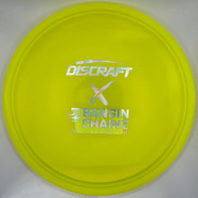 A bright yellow Discraft Bangin' Chainz disc golf disc resting on a white surface.
