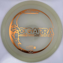 A translucent pale yellow disc golf disc with metallic gold foil stamping of the 'SCORPA' model name and mountain graphic, resting on a white surface.