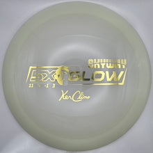 A translucent pale yellow disc golf disc with gold foil stamping, shown inside its white packaging insert.