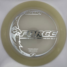 A Discraft Force distance driver disc golf disc in Mega Glo translucent plastic, featuring a silver foil stamp with the Discraft logo and a wolf graphic, shown on its white backing card.
