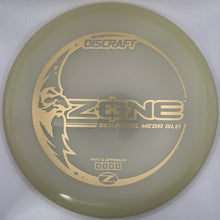 A translucent olive-green Discraft Z-One Serpental Mega Gold disc golf disc with gold foil stamping, shown inside its white packaging sleeve.