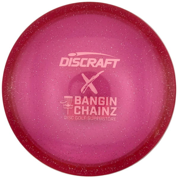 A pink Discraft Bangin' Chainz X disc golf disc with a glittery finish and white printed logo, shown inside its white packaging box.