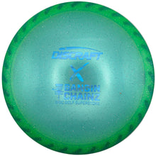 A green and blue translucent Discraft Samin Chairz golf disc with a glitter finish, displayed on a white surface.
