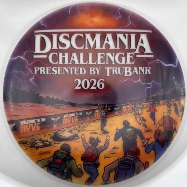 A circular Discmania Challenge 2026 button badge featuring an illustrated scene of people running through a desert landscape under a stormy sky with lightning, presented by TruBank.