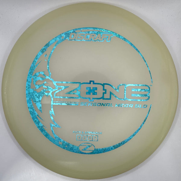 A disc golf disc, specifically a One Ring Zenn disc, in its white retail packaging. The disc features a translucent pale yellow-green body with a prominent metallic blue holographic foil stamp of the 'ZENN' model name and a circular logo.