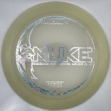 A Discraft Nuke Special Mega Gold disc golf disc in a translucent pale gold color with a holographic silver foil stamp, shown inside its white packaging insert.