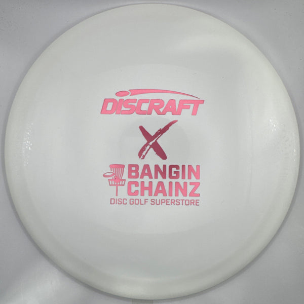 A white Discraft x Bangin' Chainz disc golf superstore disc with pink printed logos, shown inside its white packaging sleeve.