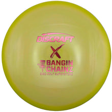A yellow Discraft X Bangin' Chainz disc golf disc with pink lettering, shown inside its white packaging box.