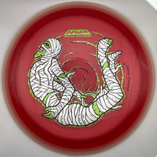 A red disc golf disc with a mummy illustration in white and green, displayed inside a white circular holder.