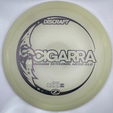 A Discraft Cigarra Sersonal Mega Glo disc golf driver in a translucent pale yellow-green plastic, resting on a white foam insert.