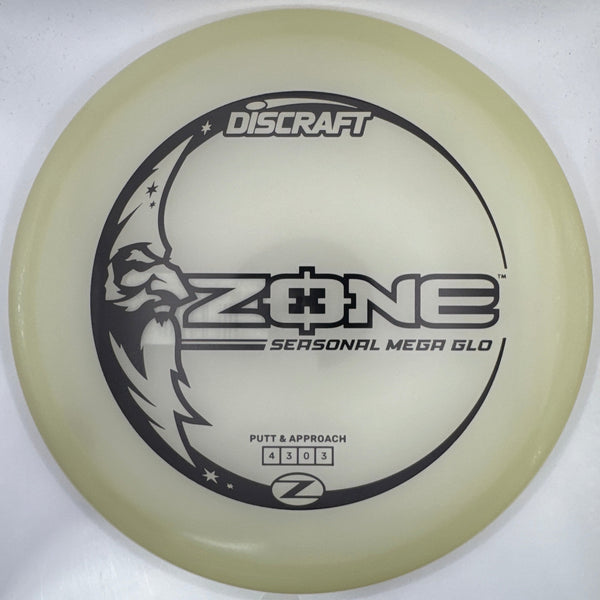 A translucent pale yellow Discraft ZONE disc golf disc with black printed graphics, shown inside its white retail packaging.
