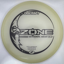 A translucent pale yellow Discraft ZONE disc golf disc with black printed graphics, shown inside its white retail packaging.