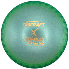 A Discraft X Bangin' Chainz disc golf disc with a green-to-blue gradient and gold foil stamp, resting on a white surface.