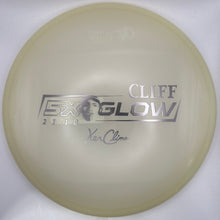 A translucent pale yellow disc golf disc with silver foil stamping that reads 'CLIFF GLOW' and 'Yan Klem' on a white backing card.
