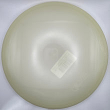 A round, translucent off-white plastic or silicone insert, likely a lens protector or protective cover, resting on a white foam insert with a barcode sticker on it.