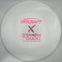 A white Discraft disc golf disc with pink printed branding, shown inside its white retail packaging.