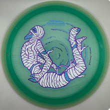 A translucent green disc golf disc with a purple and white illustrated design of two wrapped figures, photographed inside a circular opening against a white background.
