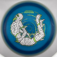 A blue disc golf disc with a white and green mummy graphic and the MVP logo, photographed from directly above inside a white circular frame.