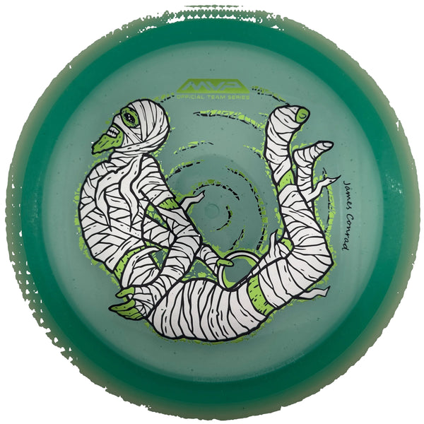A translucent green disc golf disc with a white and black illustrated mummy design and lime green accents, photographed from directly above inside a white circular holder.