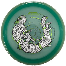 A translucent green disc golf disc with a white and black illustrated mummy design and lime green accents, photographed from directly above inside a white circular holder.